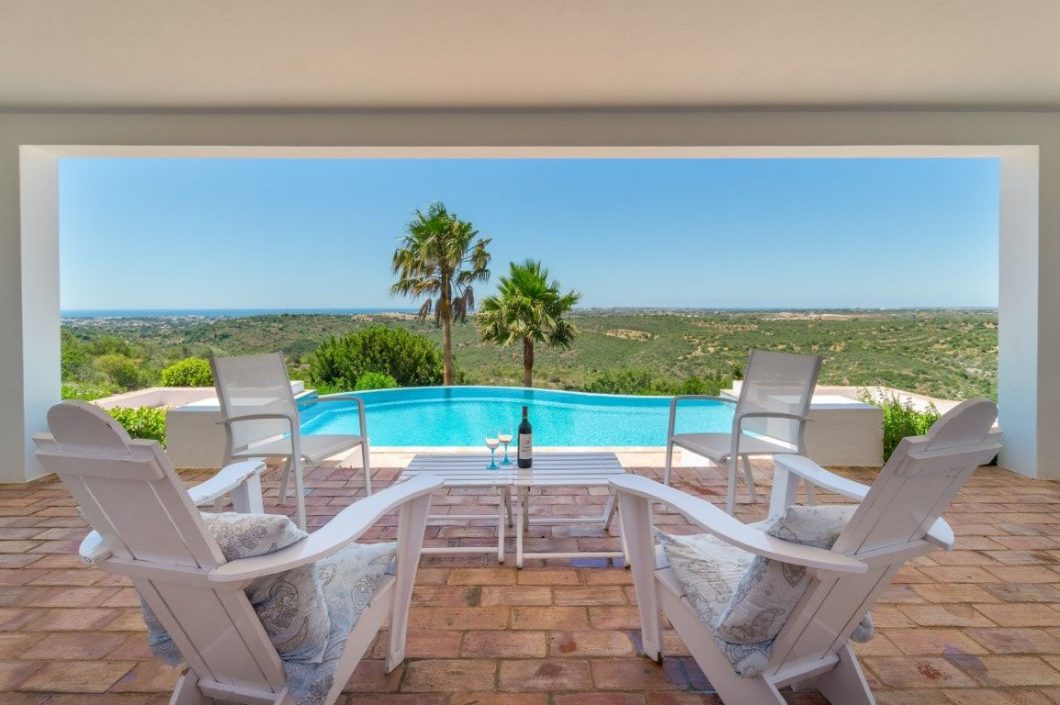 four chairs and table by the pool overlooking an amazing landscape
